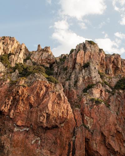 Spiky red granite cliffs and jagged rock spires rise against a blue sky.