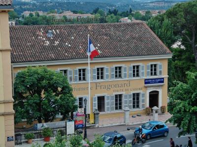 A yellow building with a tiled roof, French flag, and signage reading "Parfumerie Fragonard" and "Musée du Parfum" in Grasse, France.