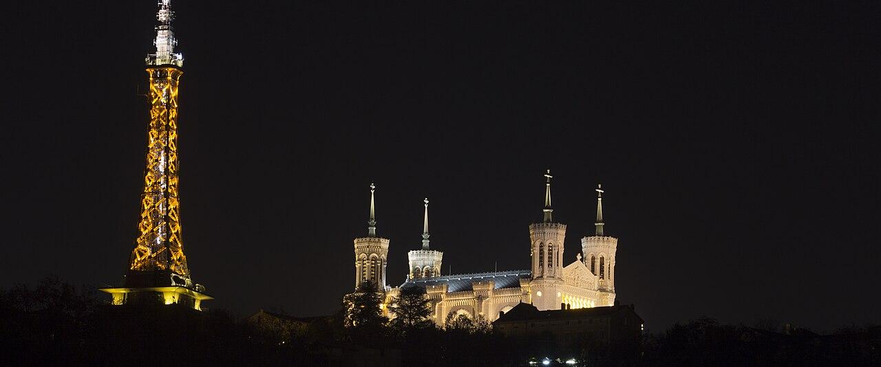 The basilica of Notre-Dame de Fourvière and the metal tower lit up at night above Lyon