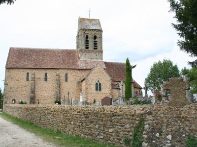 A stone church with a tiled roof and bell tower, situated behind a low stone wall that encloses a cemetery with visible crosses and headstones.