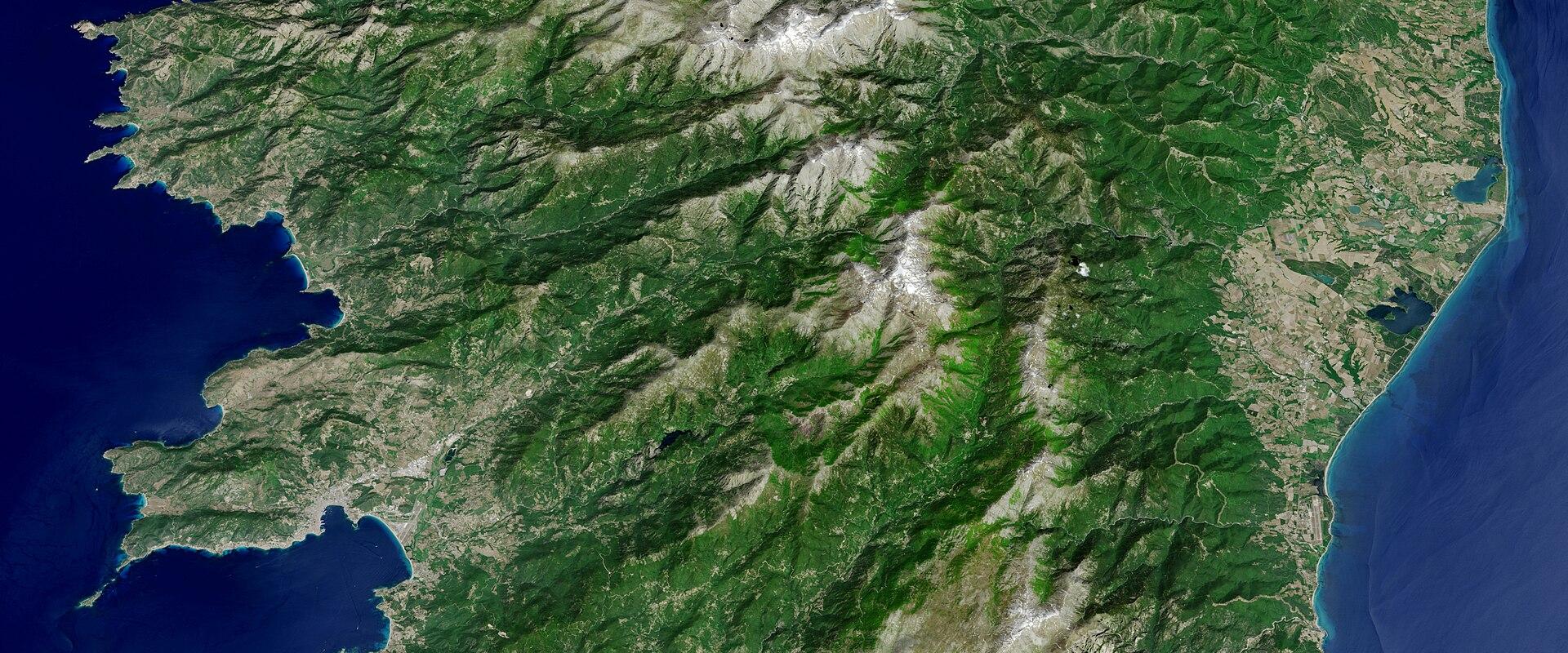 1. A satellite or aerial map view of the island of Corsica, showing its mountainous interior and surrounding Mediterranean sea.