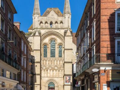 The image shows the south facade of a Gothic cathedral with two prominent spires, arched windows, and a central entrance, situated at the end of a narrow street lined with brick buildings; visible signage includes "RUE SAINT-CRÉPIN" and "ADREA," i
