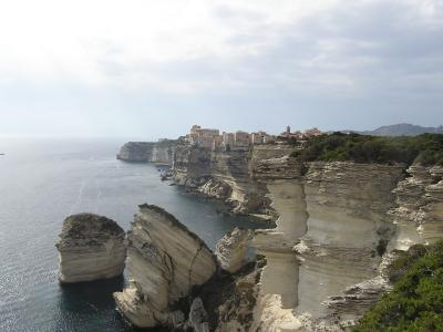 Bonifacio perched on white limestone cliffs above the sea, with the Grain de Sable rock, Corsica