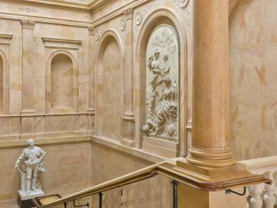 The grand marble staircase inside the Palace of the Dukes of Burgundy, featuring sculptures and inscriptions of famous writers.