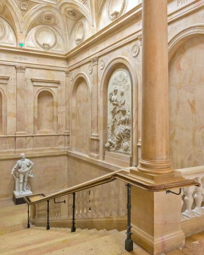 The grand marble staircase inside the Palace of the Dukes of Burgundy, featuring sculptures and inscriptions of famous writers.