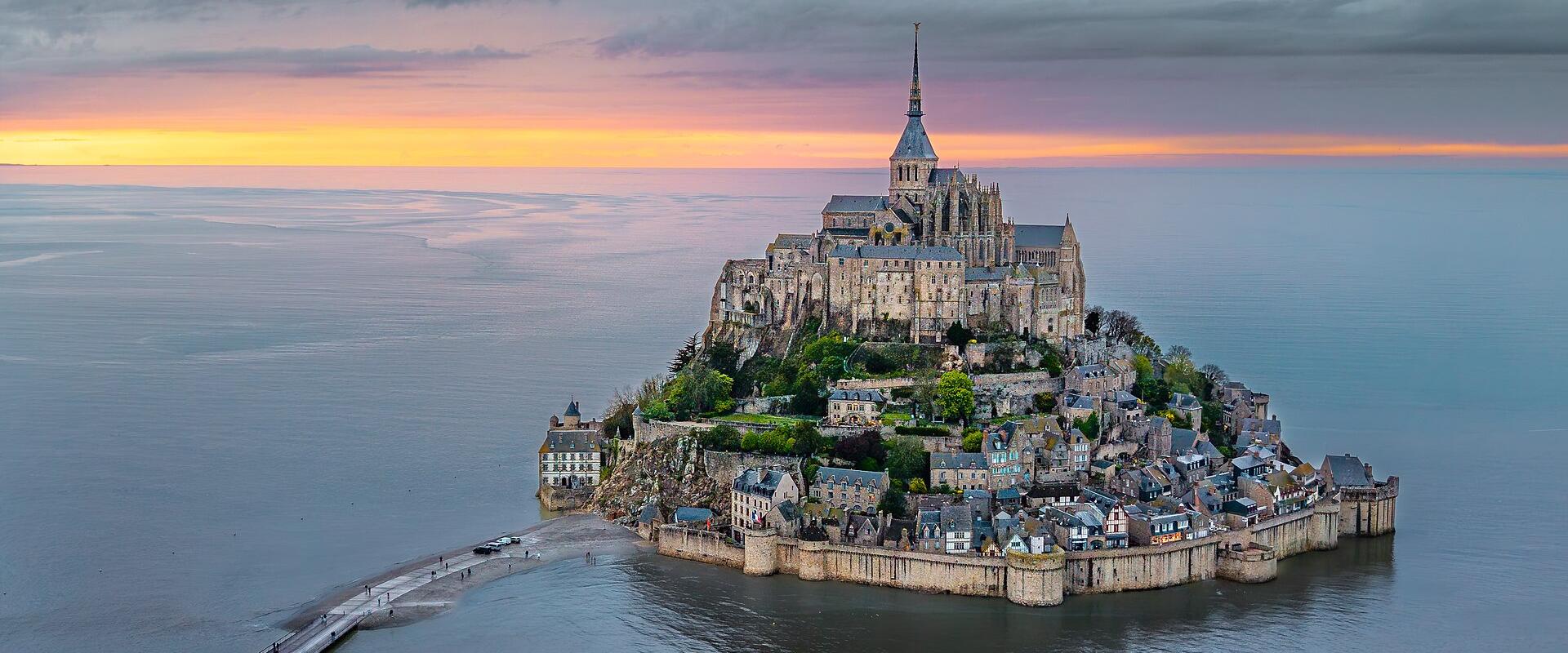 Mont-Saint-Michel and its causeway rising from the bay at sunset, Normandy