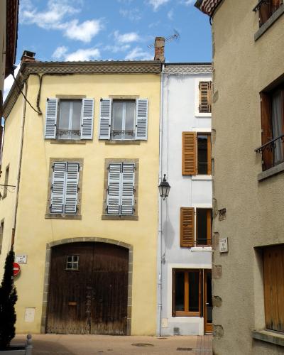 A narrow street scene featuring a yellow building with white shutters and a large wooden garage door, alongside a white building with brown shutters, under a blue sky.