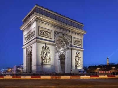 Illuminated Arc de Triomphe at twilight with Eiffel Tower in background.