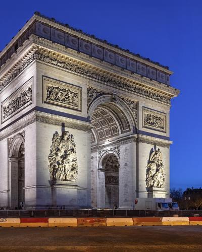 Illuminated Arc de Triomphe at twilight with Eiffel Tower in background.