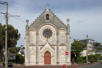 1. The image shows the facade of the Église Notre-Dame-des-Anges in Royan, France, a stone church with a large rose window, arched doorway, and a cross atop the gable, situated at a street corner with utility poles and a red "no entry" sign.
