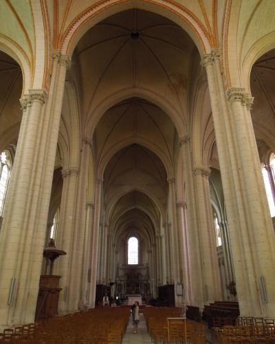 A view down the central nave of a Gothic church with rows of wooden pews.