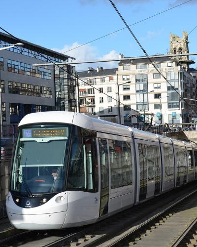 A white Alstom Citadis 302 tram (number 854) on tracks in an urban setting, with a station platform visible on the right and buildings in the background; the destination display on the tram reads "THÉÂTRE DES ARTS".