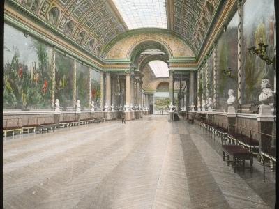 Ornate hall with glass ceiling, large murals, and marble busts.