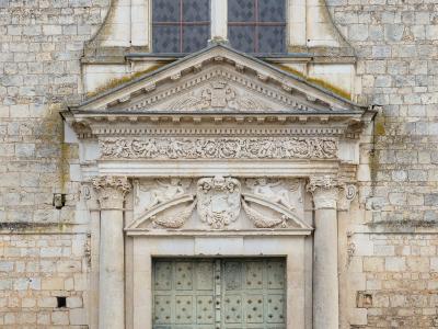 Classical stone portal with columns and pediment on a historic church facade.