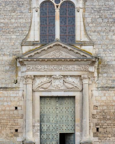 Classical stone portal with columns and pediment on a historic church facade.