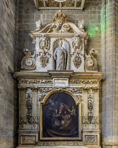 An ornate, gilded Baroque-style chapel altar featuring a statue of Saint Joseph above a religious painting, set within a stone-walled interior.
